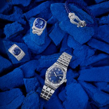Photographie de joaillerie monochrome bleue avec montre de luxe et bijoux sertis de diamants et pierres précieuses, réalisée pour un magazine de joaillerie.